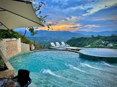 a swimming pool with chairs and an umbrella at Monteclaro Campestre - En Sopetran in Sopetran
