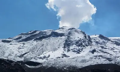 a snow covered mountain with smoke coming out of it at Habitación privada in Manizales