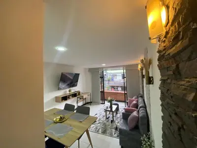 a living room with a table and a stone wall at Apartamento Cozy in Medellín