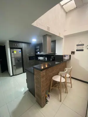 a kitchen with a counter and two chairs in it at Apartamento Cozy in Medellín
