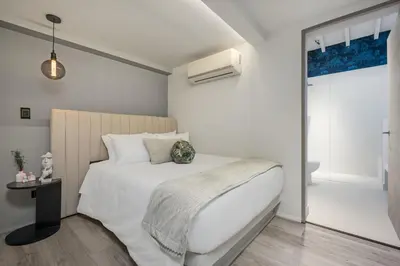 a white bedroom with a bed and a bathroom at Nago Hometel Boutique in Medellín