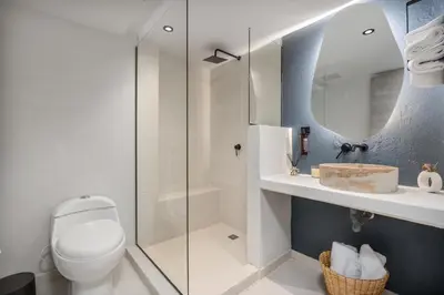a bathroom with a toilet and a glass shower at Nago Hometel Boutique in Medellín