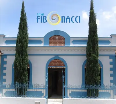 a blue and white building with two trees in front at Casa Fibonacci in Titiribí