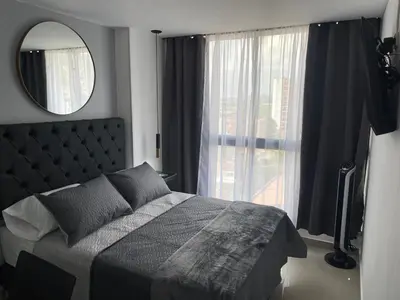 a bedroom with a bed and a mirror and a window at Urbanlifestudios in Medellín