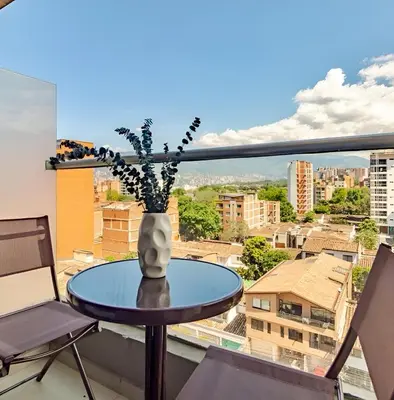 a table with a vase of flowers on a balcony at Urbanlifestudios in Medellín
