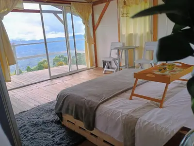 a bedroom with a bed with a table and a balcony at Chalet Campestre San Gabriel in Angostura