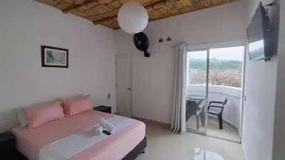 a bedroom with a bed and a table and a window at Hotel campestre París soleil in Mariquita
