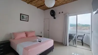 a bedroom with a pink bed and a balcony at Hotel campestre París soleil in Mariquita