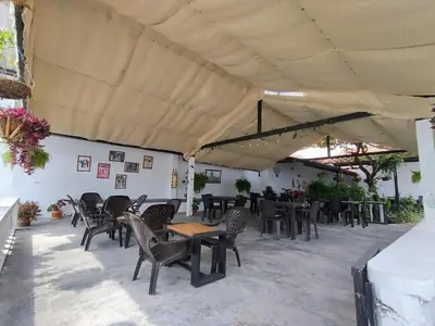 a patio with tables and chairs under a roof at Hotel campestre París soleil in Mariquita
