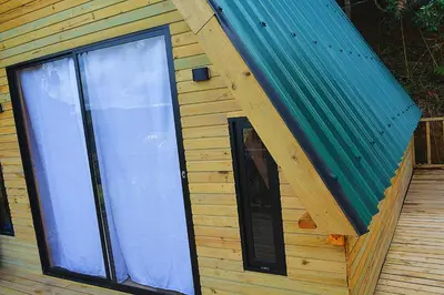 a building with a large window and a green roof at Cabaña Madre Selva in San Vicente