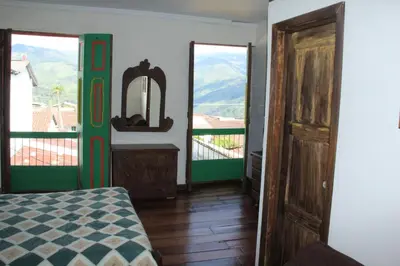 a room with a bed and a mirror and a balcony at Hotel Colonial - Salamina Caldas in Salamina