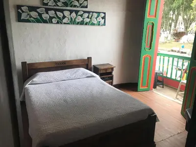 a bedroom with a bed and a door to a balcony at Hotel Colonial - Salamina Caldas in Salamina