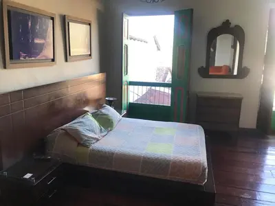 a bedroom with a bed and a window and a mirror at Hotel Colonial - Salamina Caldas in Salamina
