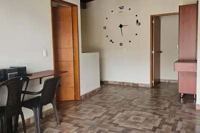 a room with a table and a clock on the wall at Espacioso y lindo lugar in Bello