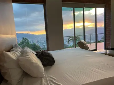 a bedroom with a large white bed with a view at Poblado Villa Great views Nature Jacuzzi Security in Medellín