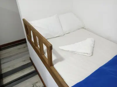 a small bed with white sheets and a pillow on it at Casa Finca Hotel Loma Encantada in Guatapé