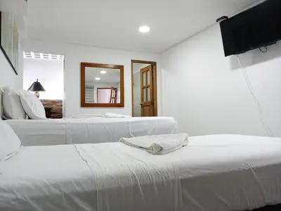 two white beds in a white room with a mirror at Casa Finca Hotel Loma Encantada in Guatapé