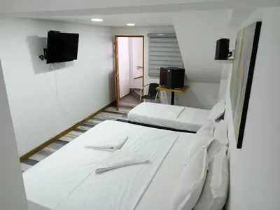 a room with two beds and a tv on the wall at Casa Finca Hotel Loma Encantada in Guatapé