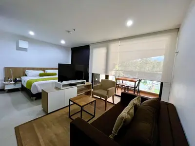 a bedroom with a couch and a bed and a television at Nmadas digitales - Hotel Rioverde in San Antonio de Pereira