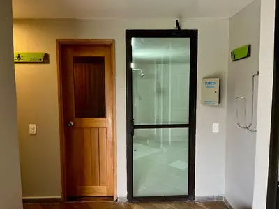 a glass shower in a room next to a door at Nmadas digitales - Hotel Rioverde in San Antonio de Pereira