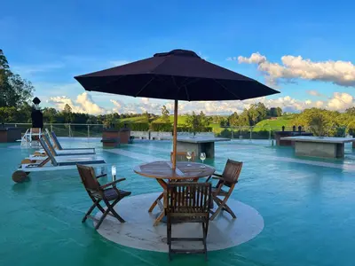 a table with chairs and an umbrella in the water at Nmadas digitales - Hotel Rioverde in San Antonio de Pereira