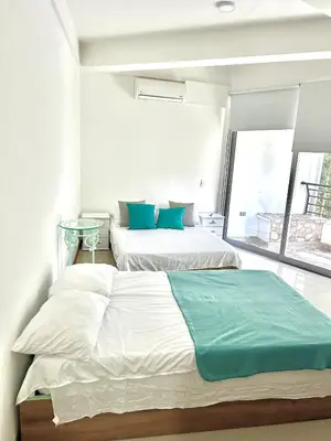 two beds in a white room with a window at Apartamento Vacacional San Jerónimo in Medellín