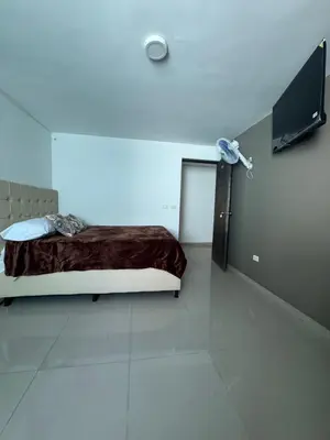 a white room with a bed and a television at Amplio apartamento en la 70 Estadio Laureles para grupos familiares o amigos in Medellín