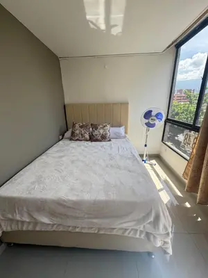 a bedroom with a bed and a large window at Amplio apartamento en la 70 Estadio Laureles para grupos familiares o amigos in Medellín