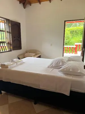 a large white bed in a room with a window at Hostal Artesanos in Jardin