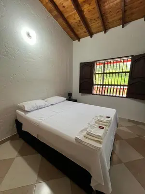 a bedroom with a large white bed with a window at Hostal Artesanos in Jardin