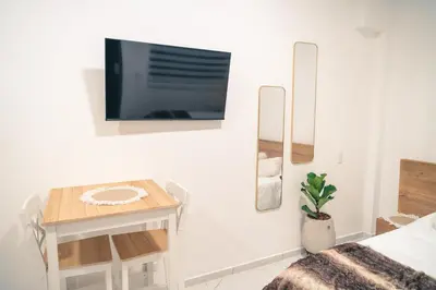 a bedroom with a tv on the wall and a table at Aparta estudio 202 - Casa Bendita in Medellín