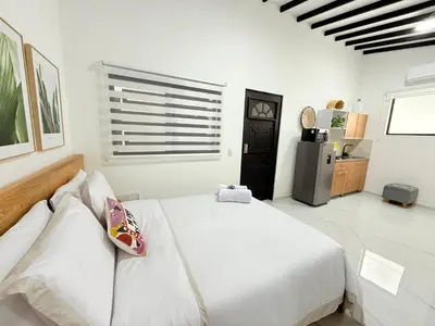 a white bedroom with a bed and a refrigerator at Aparta estudio 202 - Casa Bendita in Medellín
