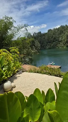 a garden with a lake and a boat in the water at Villa Deluxe Curazao in El Peñol