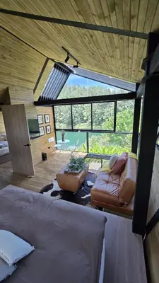 a room with a bed and a couch and a large window at Villa Deluxe Curazao in El Peñol