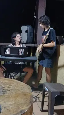 two people sitting at a table with a guitar at Finca LA CASCADA in Mesa del Norte