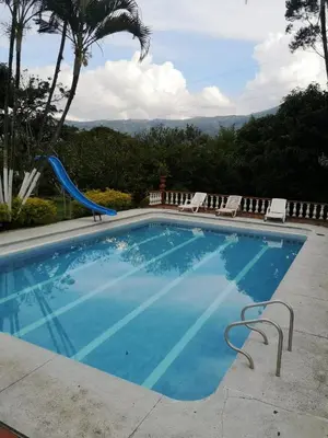 a large swimming pool with a slide and chairs at Finca Villa Cristian Copacabana Antioquia in Copacabana