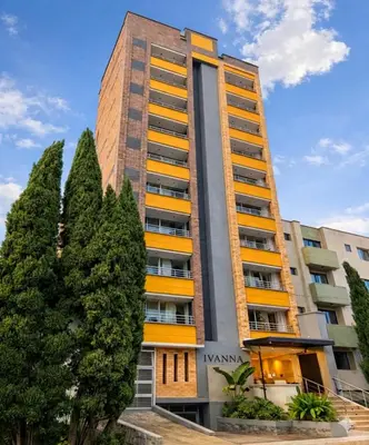 a tall building with trees in front of it at Ivanna Jumar ApartaHotel - Laureles Estadio in Medellín