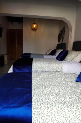 two beds in a bedroom with blue and white sheets at Casa Boutique La Corona Medellin in Envigado