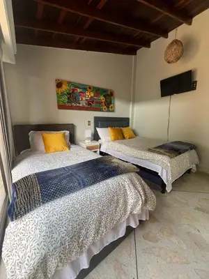 a bedroom with two beds and a flat screen tv at Casa Boutique La Corona Medellin in Envigado