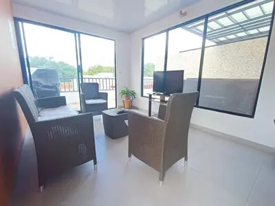 a living room with chairs and a tv and windows at CASA JAZZ Armonía y relax in Mariquita