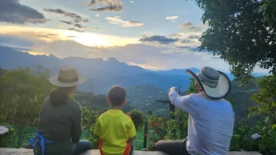 a group of people sitting on a ledge looking at the mountains at Finca Carrizales in Jardin