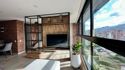a living room with a tv and a large window at Ubicación Privilegiada Laureles Medellin con Vista y AC in Medellín