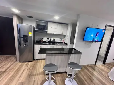 a kitchen with a bar with two stools and a refrigerator at 1905 Apto con estilo & moderno poblado in Medellín