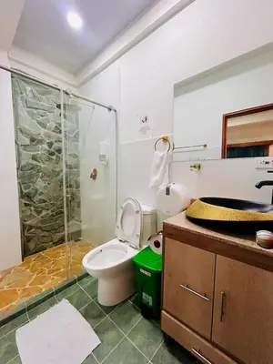 a bathroom with a toilet and a glass shower at Hotel Glorial in Doradal