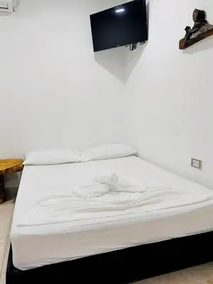 a white bed with a tv on a wall at Hotel Glorial in Doradal