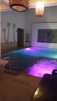 a swimming pool with purple lights in a room with palm trees at Hotel Glorial in Doradal