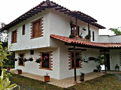 a large white house with windows and potted plants at Casa de Campo en Jardín Alojamiento Familiar in Jardin