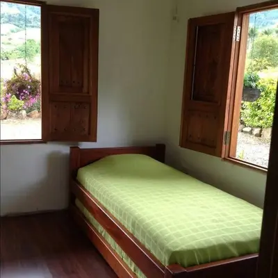a bedroom with a bed and two windows at Casa de Campo en Jardín Alojamiento Familiar in Jardin