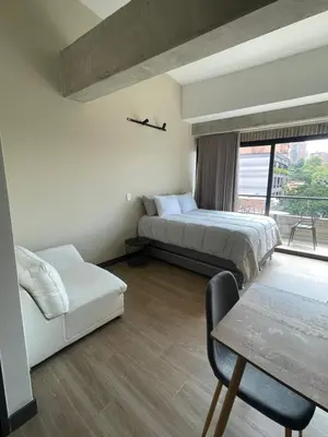 a bedroom with two beds and a table and a window at Apartamento con vista y aire acondicionado cerca a El Tesoro in Medellín