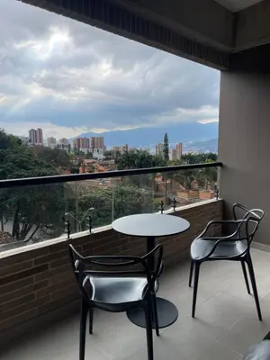 a balcony with a table and two chairs and a large window at Apartamento con vista y aire acondicionado cerca a El Tesoro in Medellín